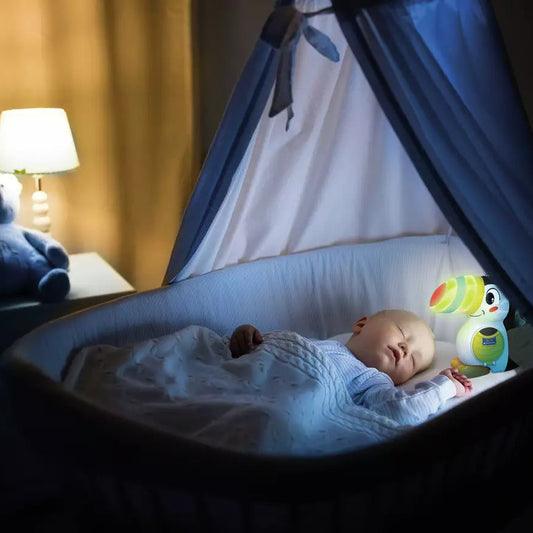 electronic toucan toy glowing in a crib with sleeping baby