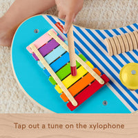 toddler playing xylophone on wooden music set 