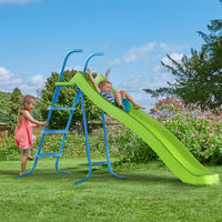 Two children playing on a green slide in a garden with a blue ladder.